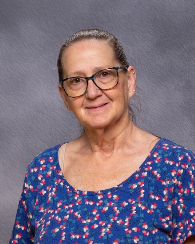 woman with brown hair, glasses, blue shirt with flowers
