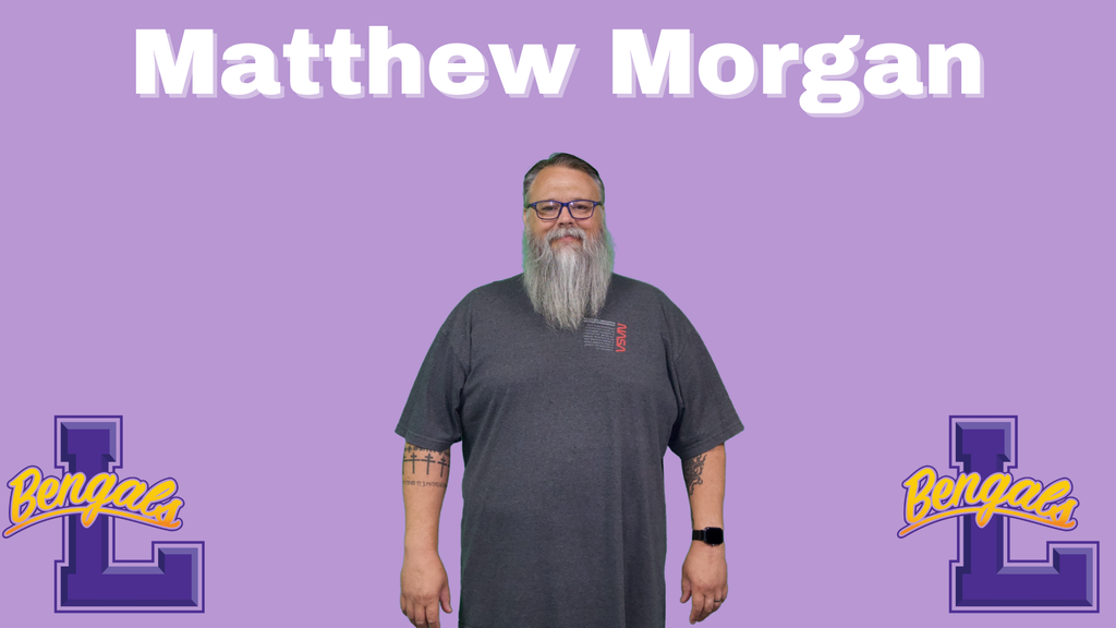 Matthew has grey hair and a long grey beard, wearing a dark grey tee shirt