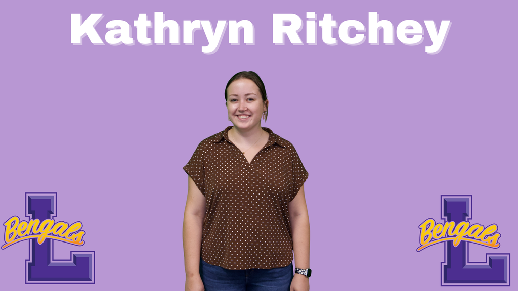 Kathryn has brown hair clipped up and is wearing a brown top