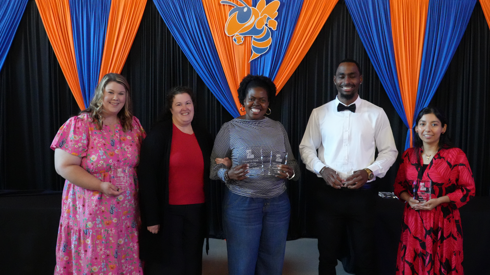 Group photo of Lexington City Schools Teacher of the Year nominees standing together during the 2026 Celebration of Excellence Ceremony in front of a blue and orange event backdrop. One honoree is not pictured in the group photo.