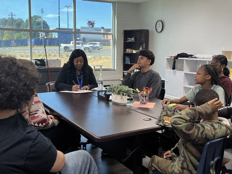 “Dr. Hardy seated at a round table with Lexington Middle School students during the Student Advisory meeting, listening to their ideas.”