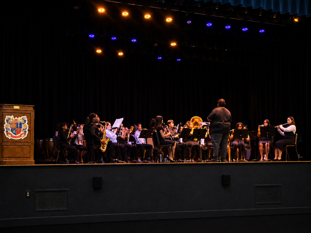 Students perform during the Lexington City Schools Spring Band Concert on stage under blue and orange lighting while audience members and families enjoy an evening of student music and performances. The concert featured student musicians playing a variety of instruments as part of the district’s spring music showcase.