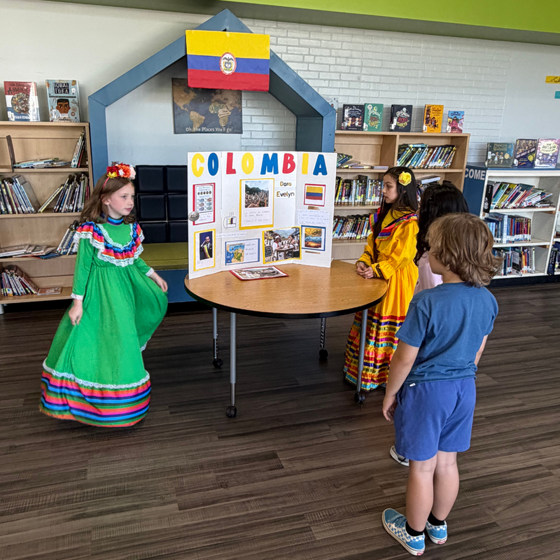 Three Pickett Elementary School students explore a Colombia-themed presentation display featuring information about the country's culture.