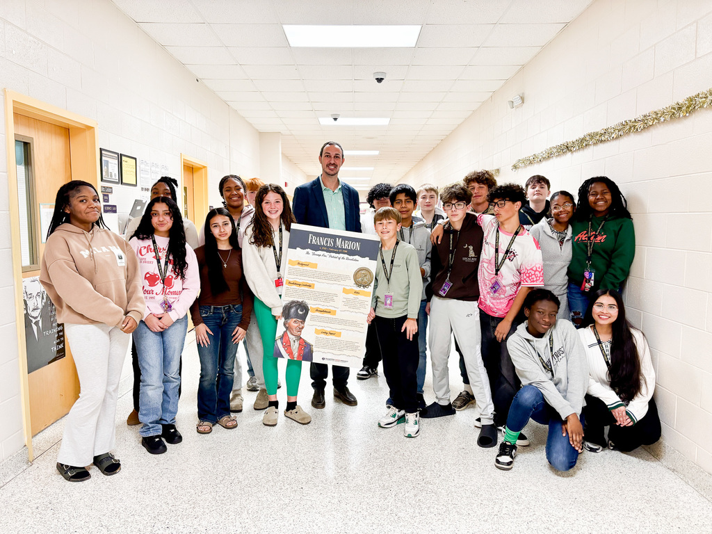 Picture of SC Teacher of the Year Corey Bedenbaugh holding a sign and surrounded by students at BLMS
