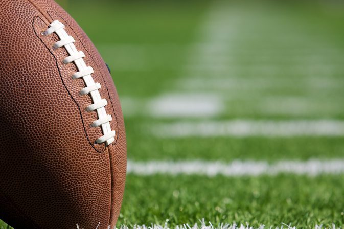 Football standing up on a tee, on a green grass field with white lines