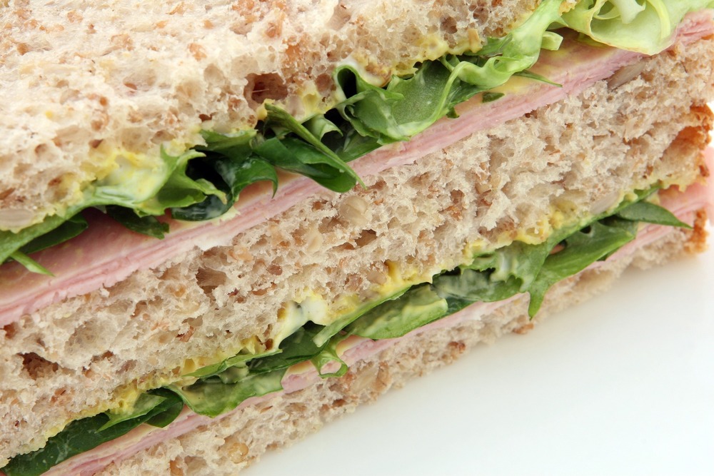 Photo of 2 halves of turkey sandwich with lettuce on wheat bread