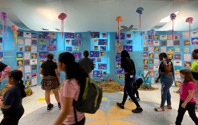 Photo of visitors walking past pictures and paintings displays at Fine Arts Night