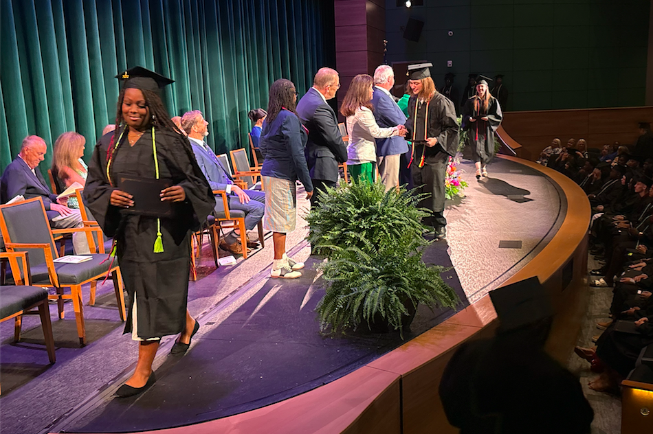 Students walk across the stage to receive their GEDs and high school diplomas