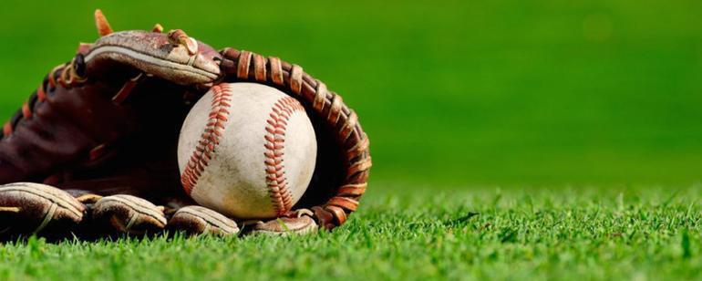 Photo of a baseball in a glove sitting on green grass