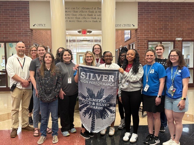 Busbee administrators, teachers,  and students hold the Palmetto Silver banner