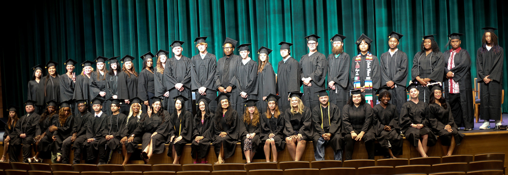 Spring 2025 adult education graduates pose for a photo on stage