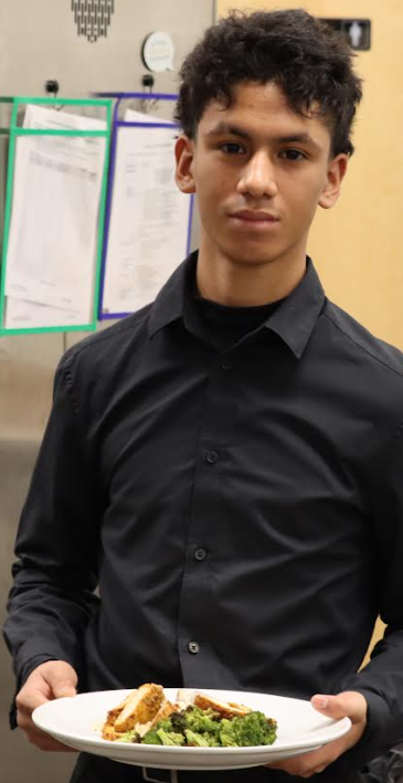 One of the students holds a plate of food in the kitchen