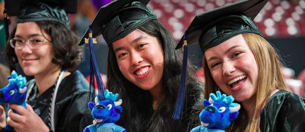 Photo of 3 girls in caps and gowns holding stuffed animals