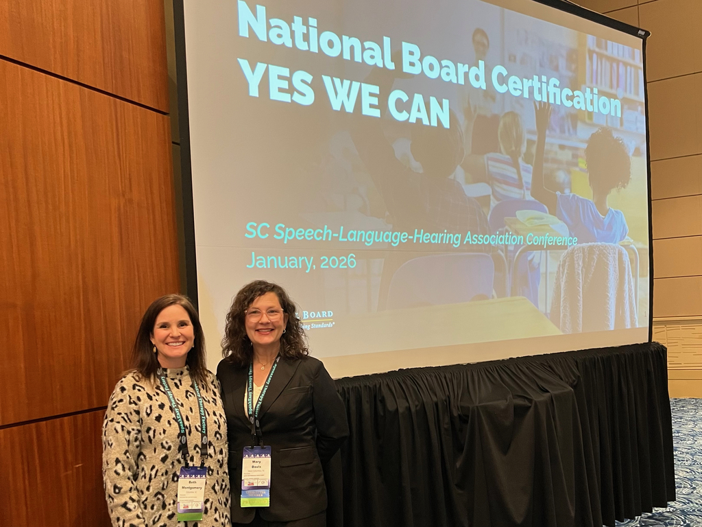 Dr. Davis and Another Woman in front of a projection screen that reads "National Board Certification YES WE CAN."