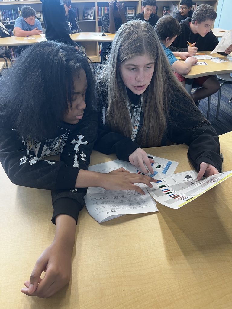 Two students compare suspect's DNA cards to the lab results from DNA found at a pretend crime scene.