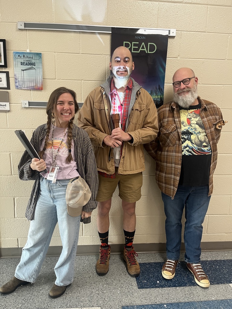 Three teachers smiling for the camera in the hallway dressed up in their camp-read-a-lot attire.