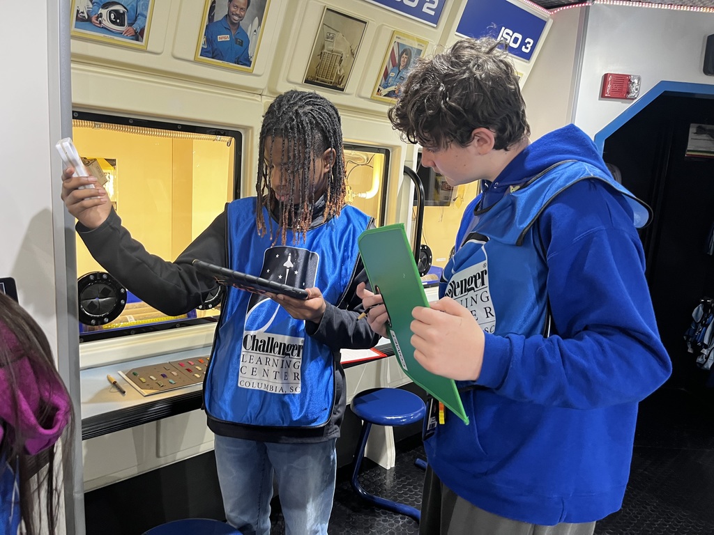 Two students test out the temperature in a space center and record their findings.