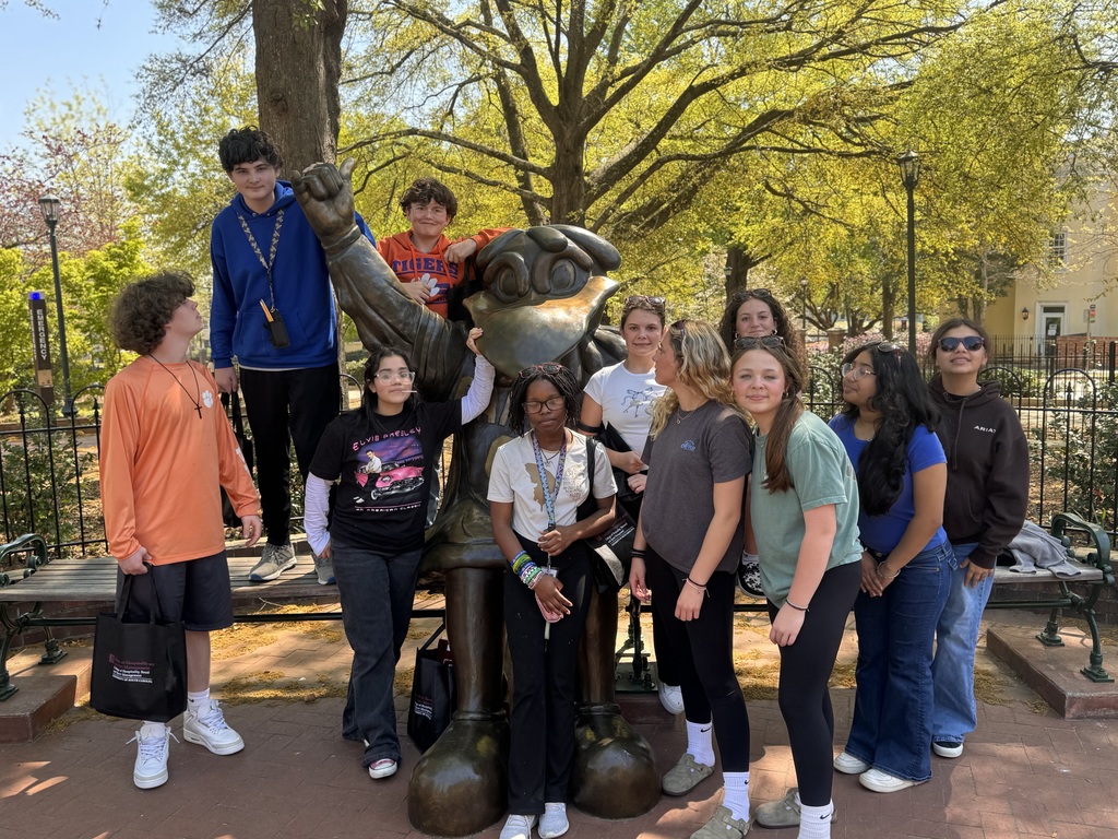 Students standing around Cocky's statue some smiling looking at the camera and others looking at each other.