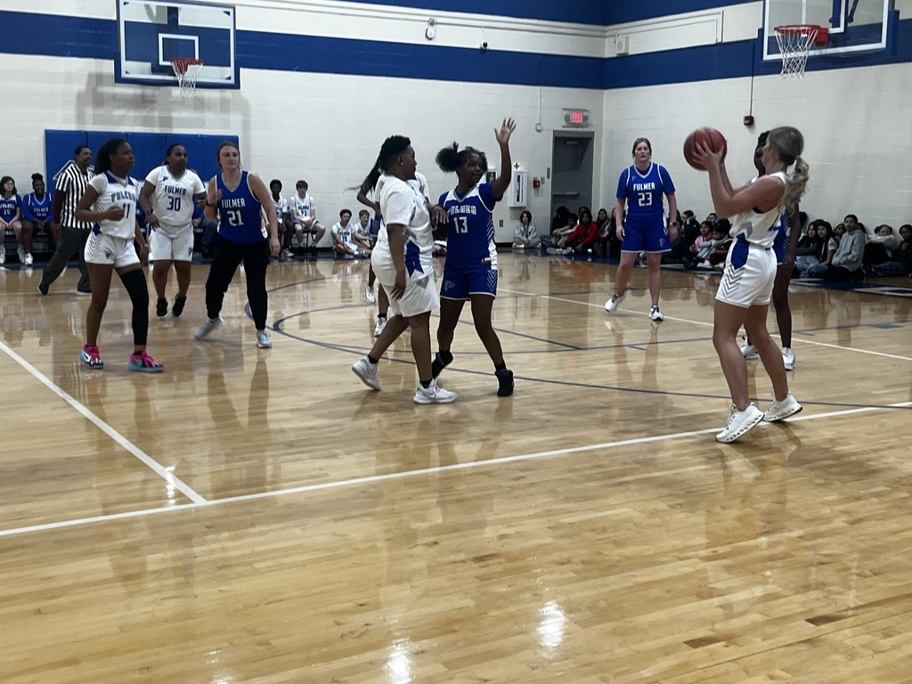 A female teacher holds the ball looking for a teammate to pass it to.