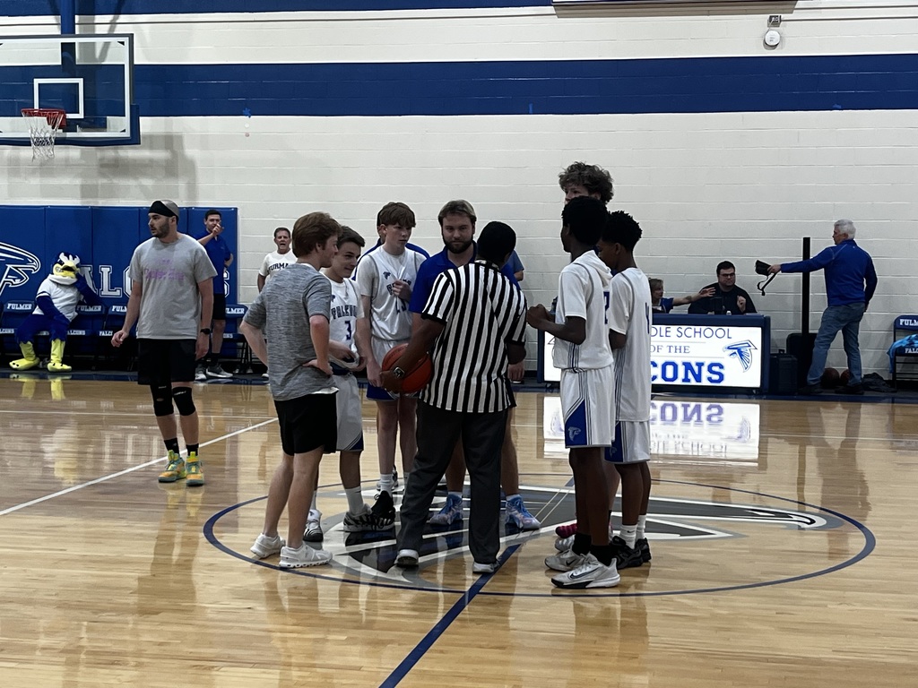 The boys talk to the referee to discuss the plan for tipoff before the boys basketball game starts.