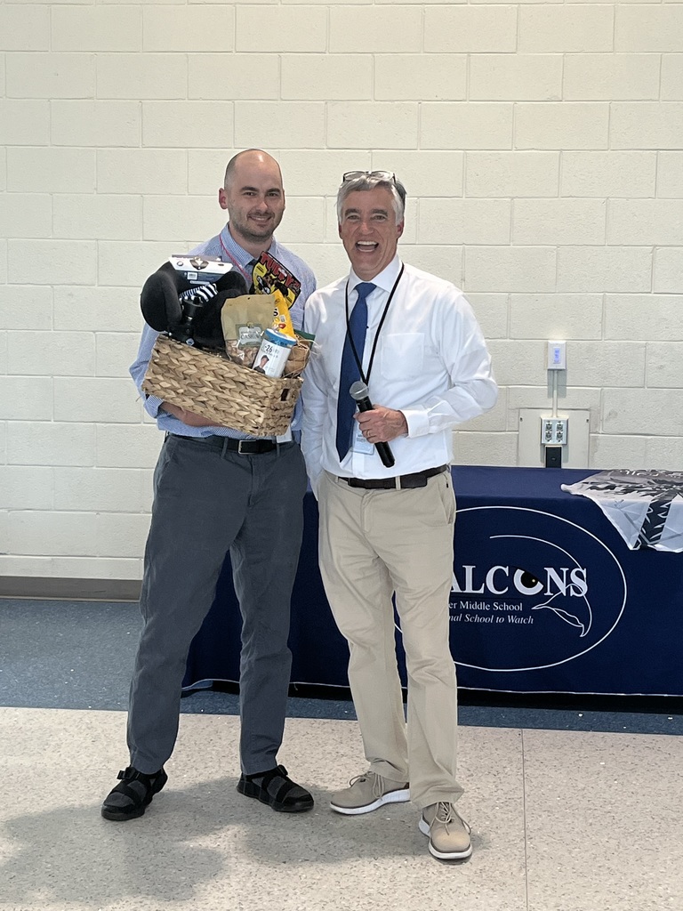 7th grade math teacher Mr. Stewart was awarded Teacher of the Year. He stands in the cafeteria beside the school principal, Mr. Wilburn smiling and holding his gift basket.
