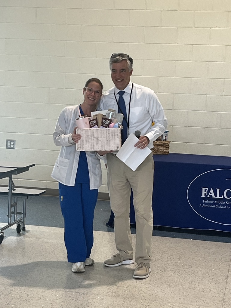 School Nurse Julie McCurdy stands beside school principal Mr. Wilburn while holding  a gift basket after being awarded Support Staff Member of the Year.