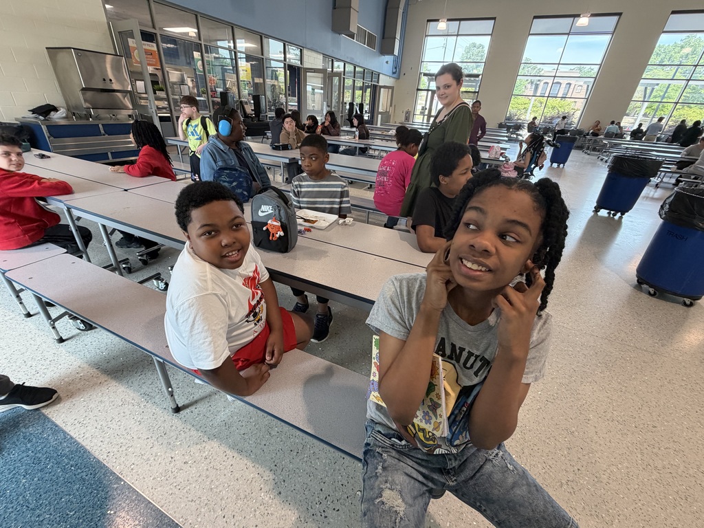 Students sit at the cafeteria table looking at the camera.