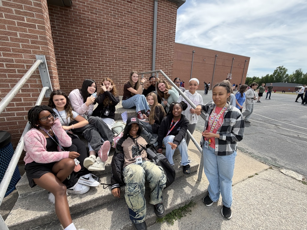 A group of female students sit on stairs outside during recess.