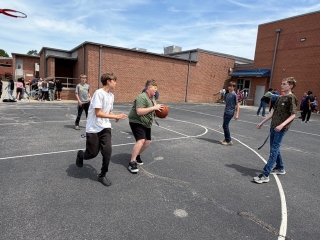 Boys play basketball on the outside blacktop during recess.