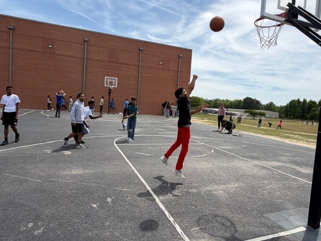 Boys play basketball on the outside blacktop during recess.