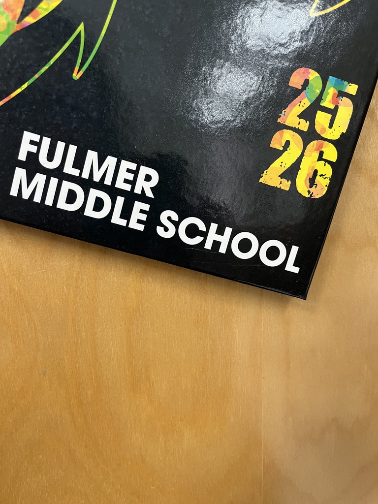 A portion of the 2025-2026 school yearbook is shown in a photo. It is the bottom portion of the book that states "Fulmer Middle School" and the number 26 in bold capital letters.