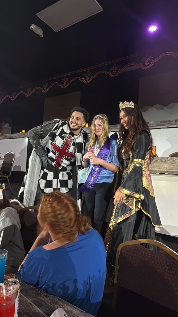 A female student was awarded Queen of the Midieval Times. She is shown with a knight and a lady dressed in clothing from that time period.