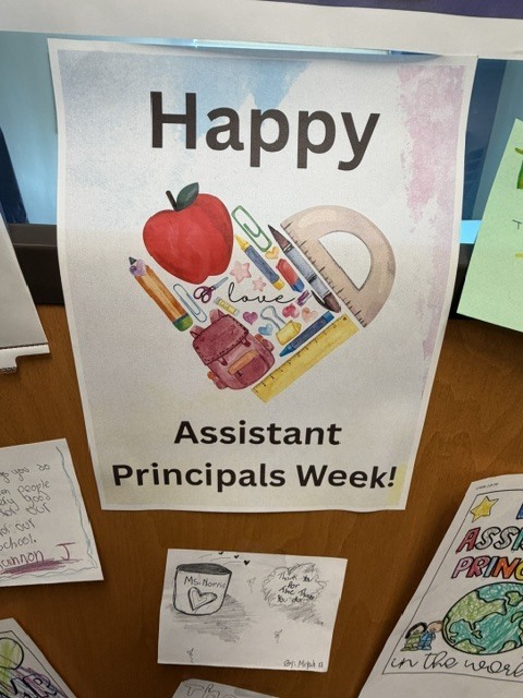 A sign taped to the window of the assistant principal's office door that states "Happy Assistant Principals Week!" and there are other small notes from students taped around the larger sign.