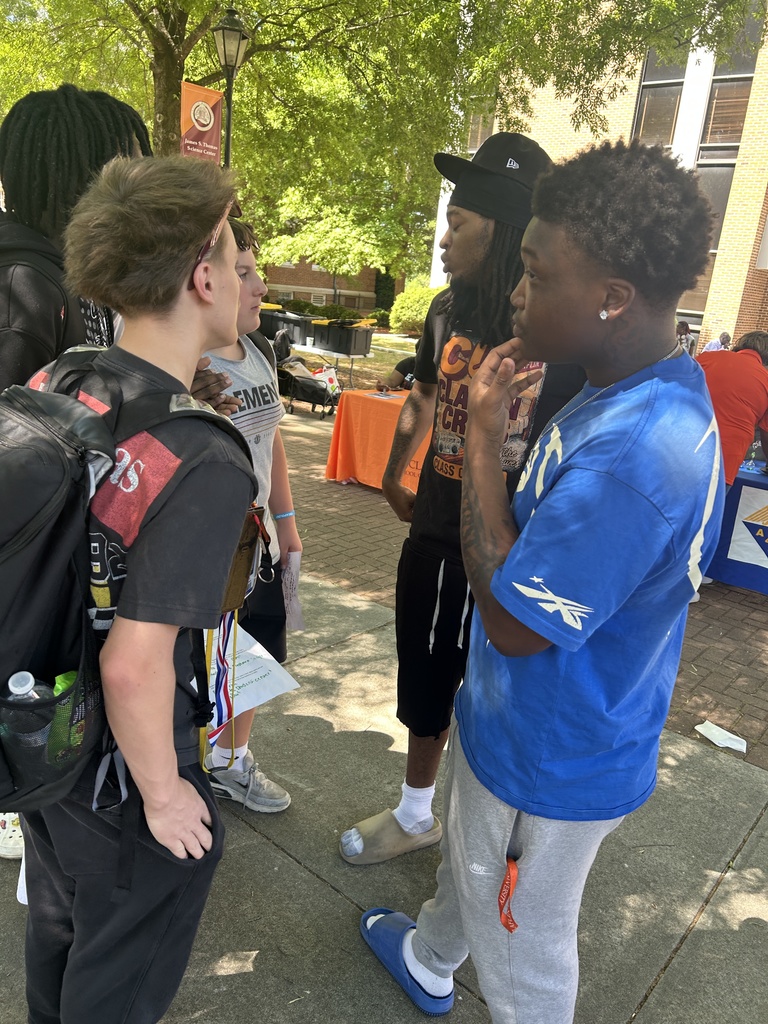 A group of students from middle school talk outside with a Clafin University Student.