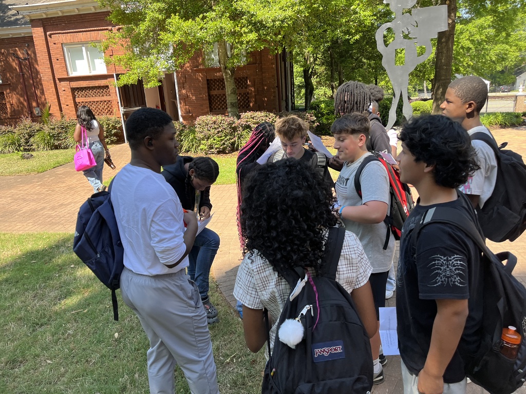 A group of students from middle school talk outside with a Clafin University Student.