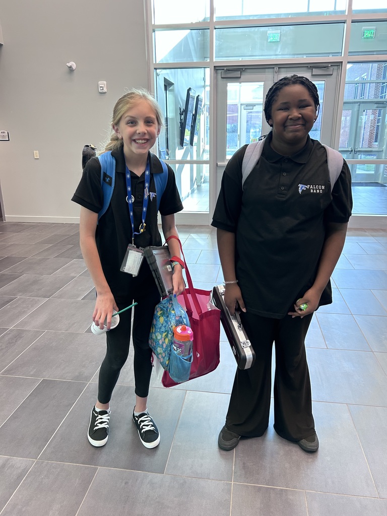 Two female students stand inside of a performing arts center. They are both looking and smiling at the camera.