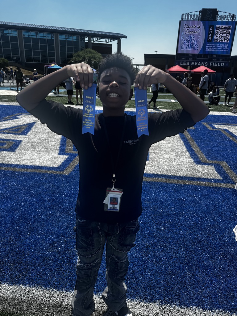 A male student holds up two blue ribbons showing he placed in two events at the Olympics.