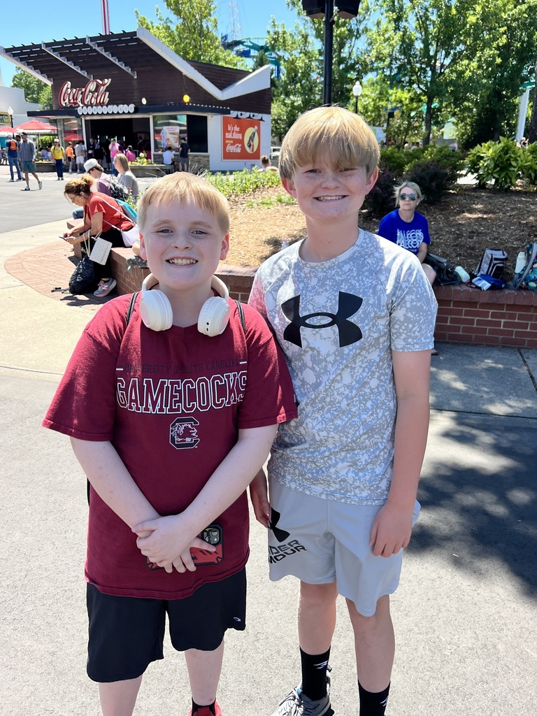Two male students stand outside at Carowinds and smile at the camera.