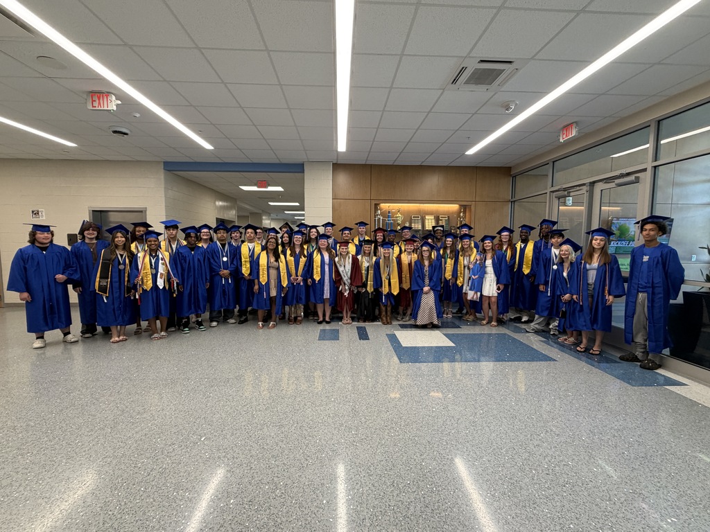 A group of senior high school students who once were students at Fulmer Middle School are dressed in their graduation regalia and standing as a group smiling for the camera.