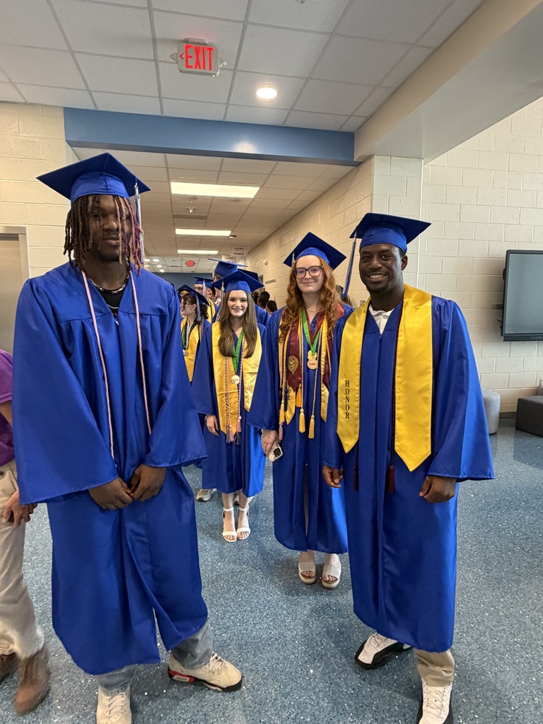 A group fo seniors stand together and smile for the camera at the beginning of their senior walk through.