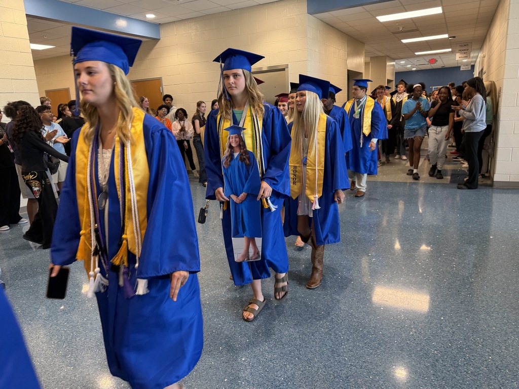 High school aged students walk through the halls of their middle school dressed in their graduation regalia for senior walk-through.