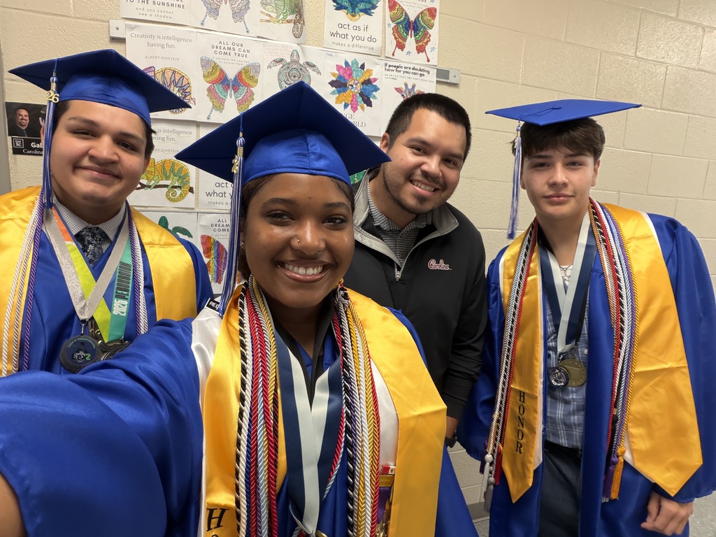 A group of senior graduates are smiling for the camera during a selfie with their once social studies teacher.