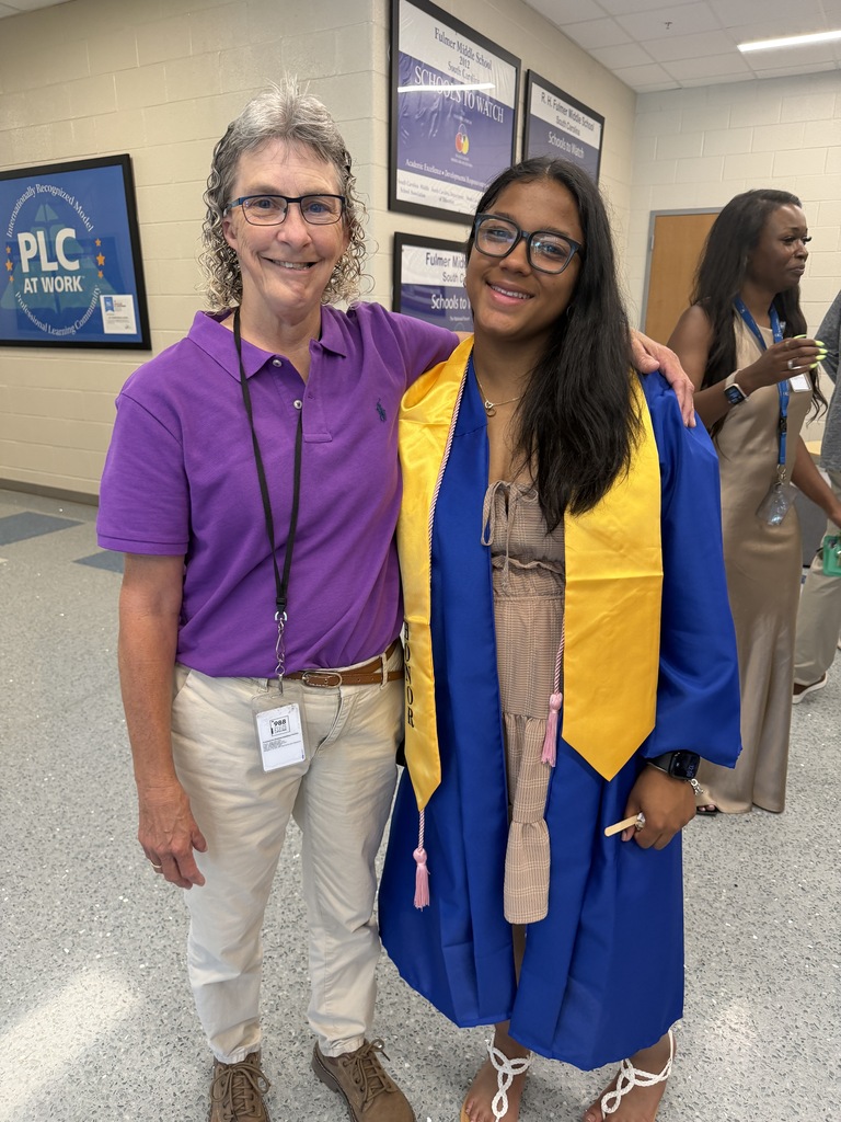 The assistant principal smiles with a senior graduate.