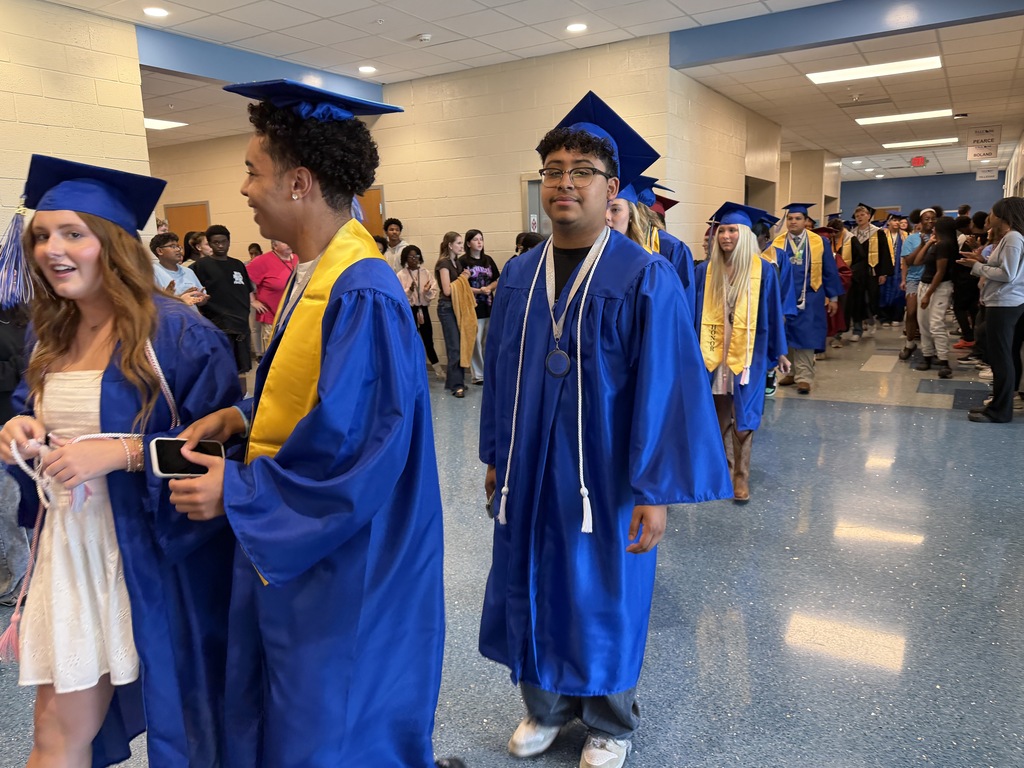 Seniors walk through the hallway in their graduation regalia for senior walk-through at their middle school.