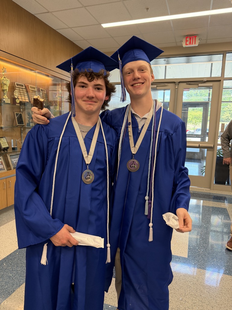 Two senior students stand in the hallway eating ice cream after their senior walk through.