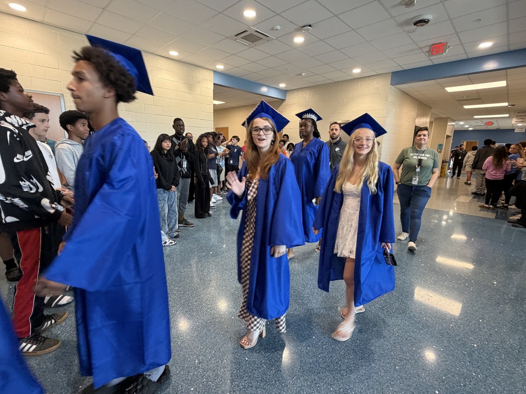 Seniors walk through the hallway in their graduation regalia for senior walk-through at their middle school.
