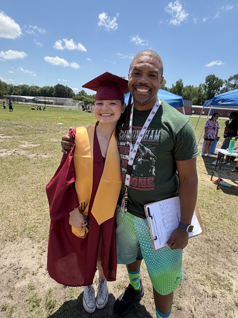 A senior student stands with her once math teacher from sixth grade while outside and in her senior regalia after senior walk through.