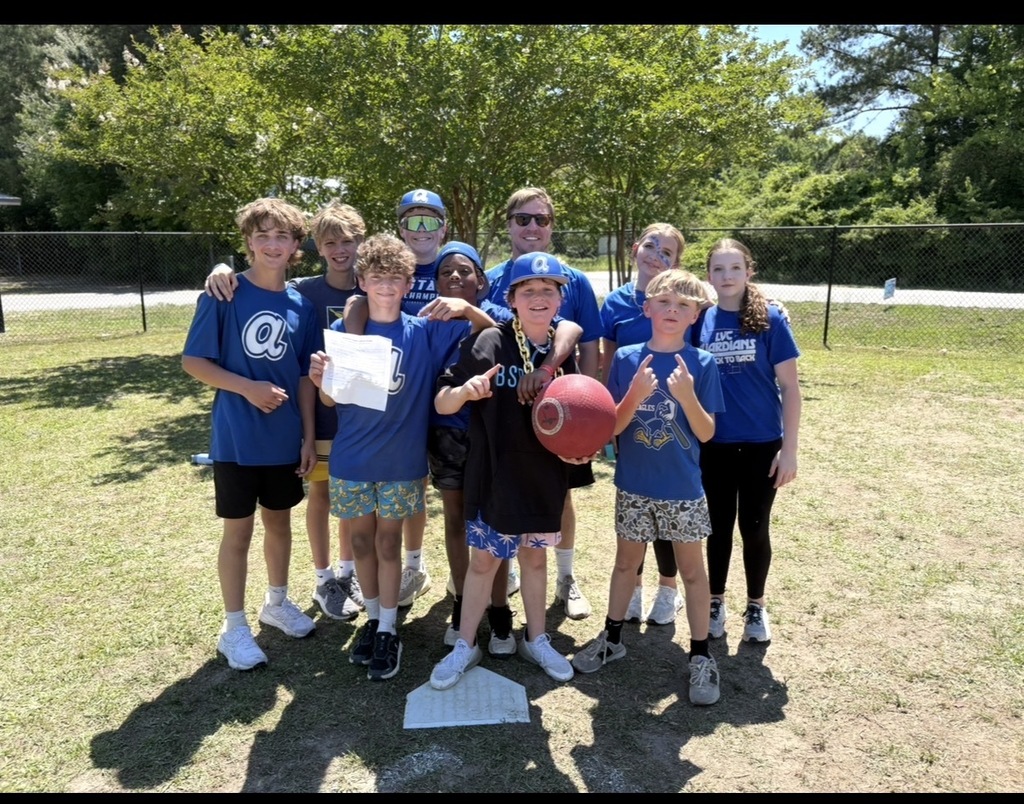The student winners and teacher of the kickball tournament stand together and smile for the picture.