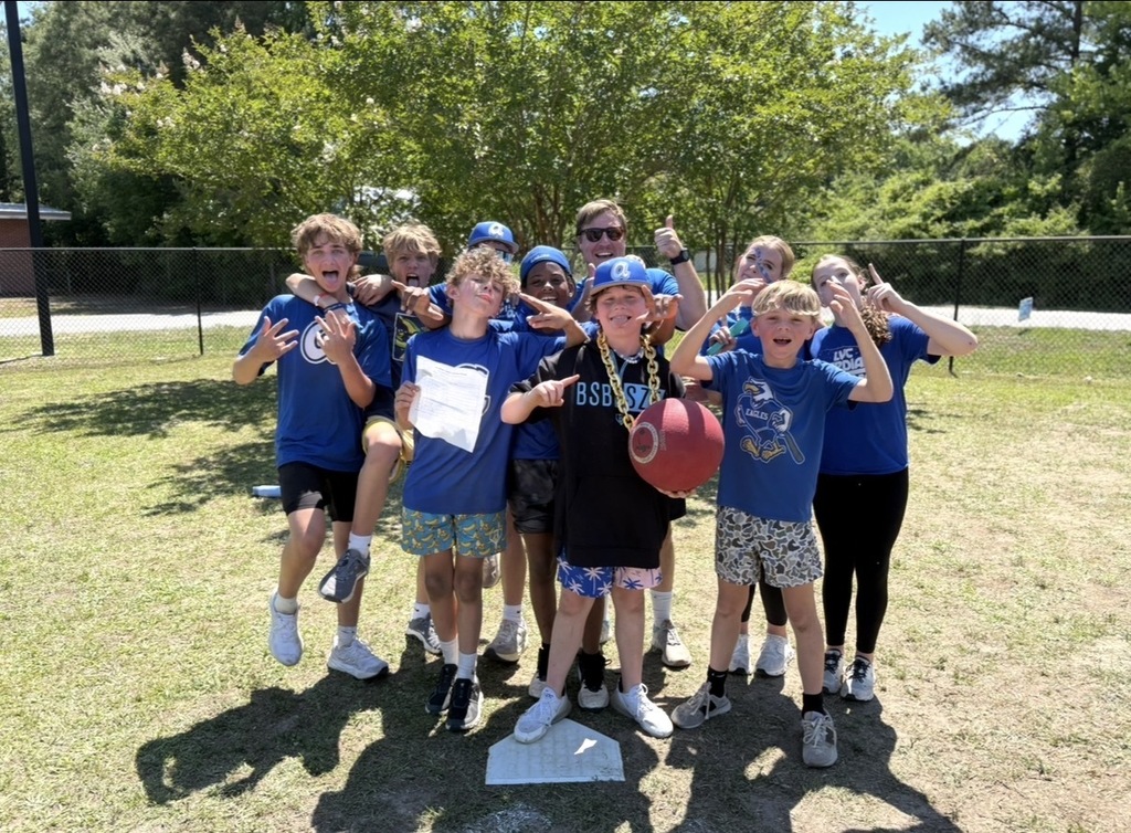 The student winners and teacher of the kickball tournament stand together and and make faces or poses for the camera.