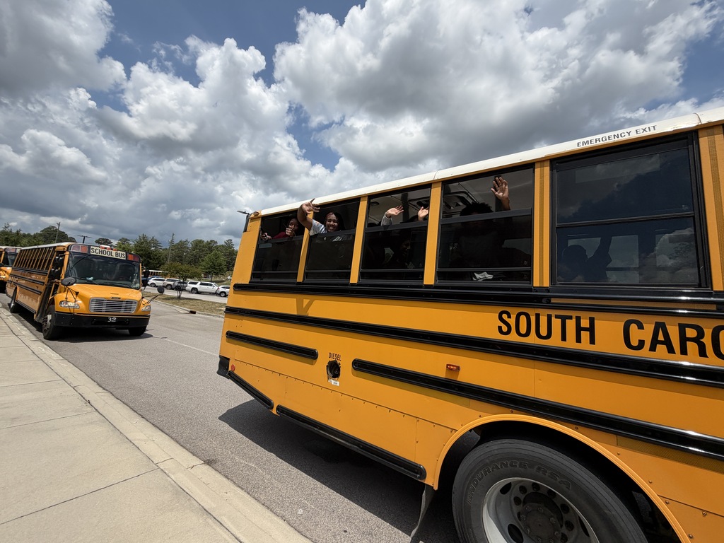 Kids on a school bus stick their hands out of the windows and wave goodbye to faculty and staff members as they leave Fulmer for summer break.